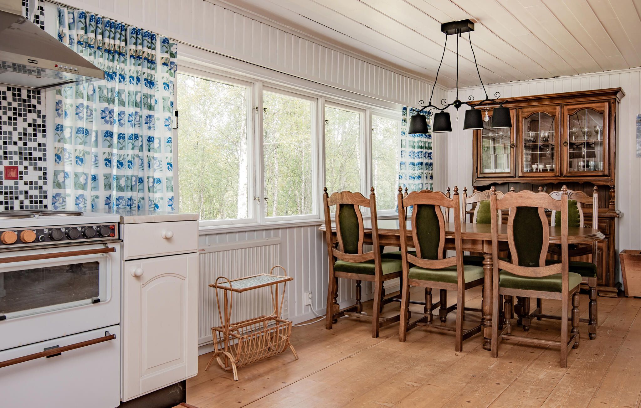 Une cuisine équipée d’une cuisinière, d’une table à manger avec des chaises et d’un meuble avec des portes en verre.