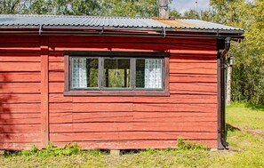 A red wooden cabin with a single window, surrounded by greenery. - Amazing home in Tärnaby with sauna (Tärnaby)