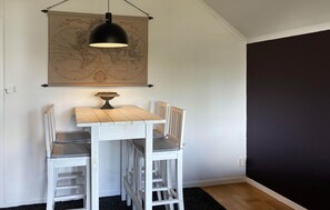 A dining area with a wooden table and chairs, a map on the wall, and a hanging light fixture. - 1 bedroom amazing apartment in Jädraås (Jädraås)