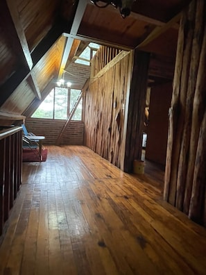 Een houten interieur met schuine wanden, een bank en een raam.