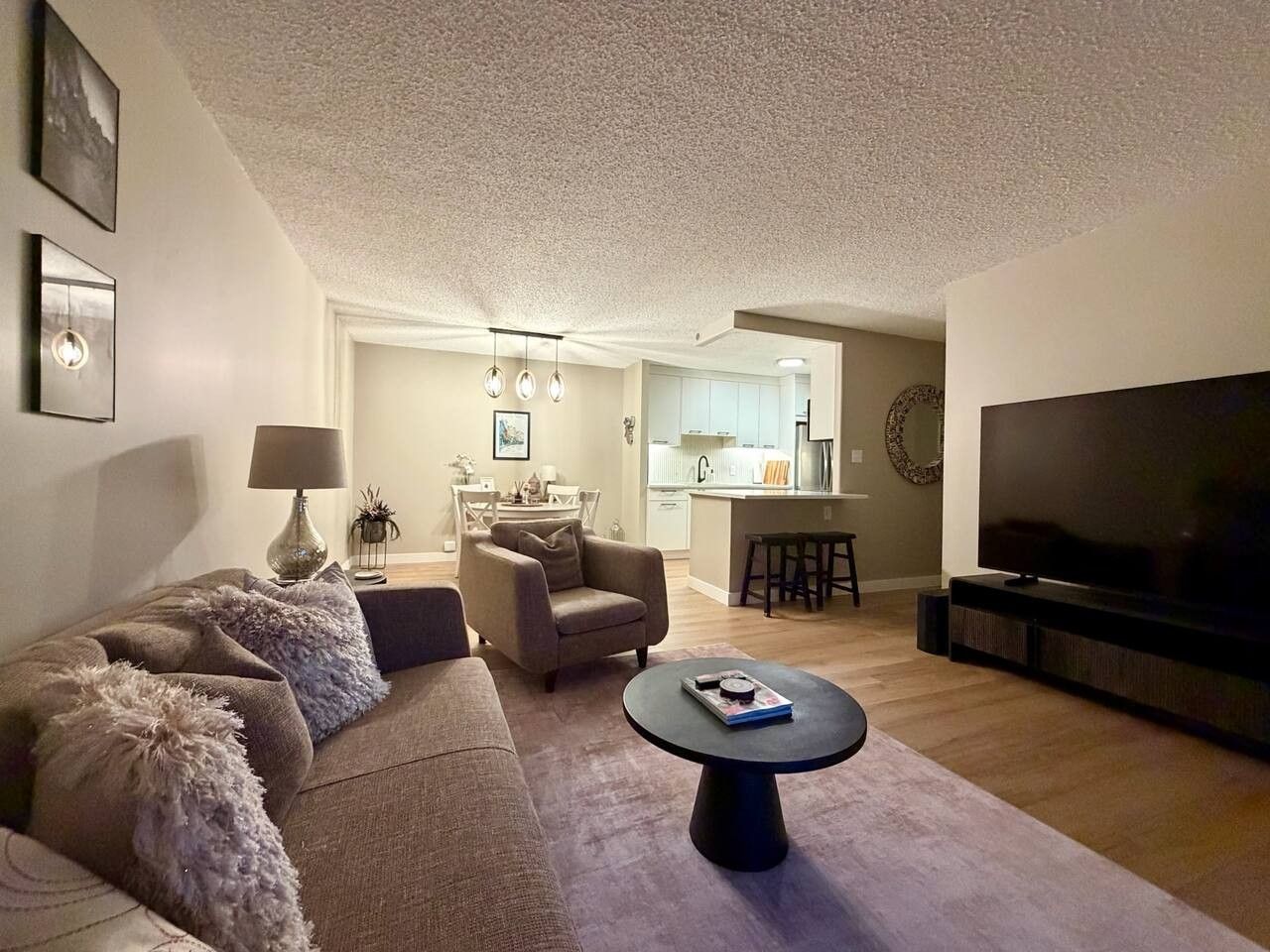 A living room with a sofa, armchair, coffee table, and a TV.