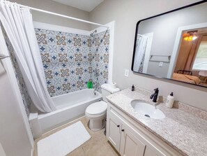 A bathroom with a shower, toilet, sink, and mirror. - Porchlight Cottage - South Bend, IN (South Bend)