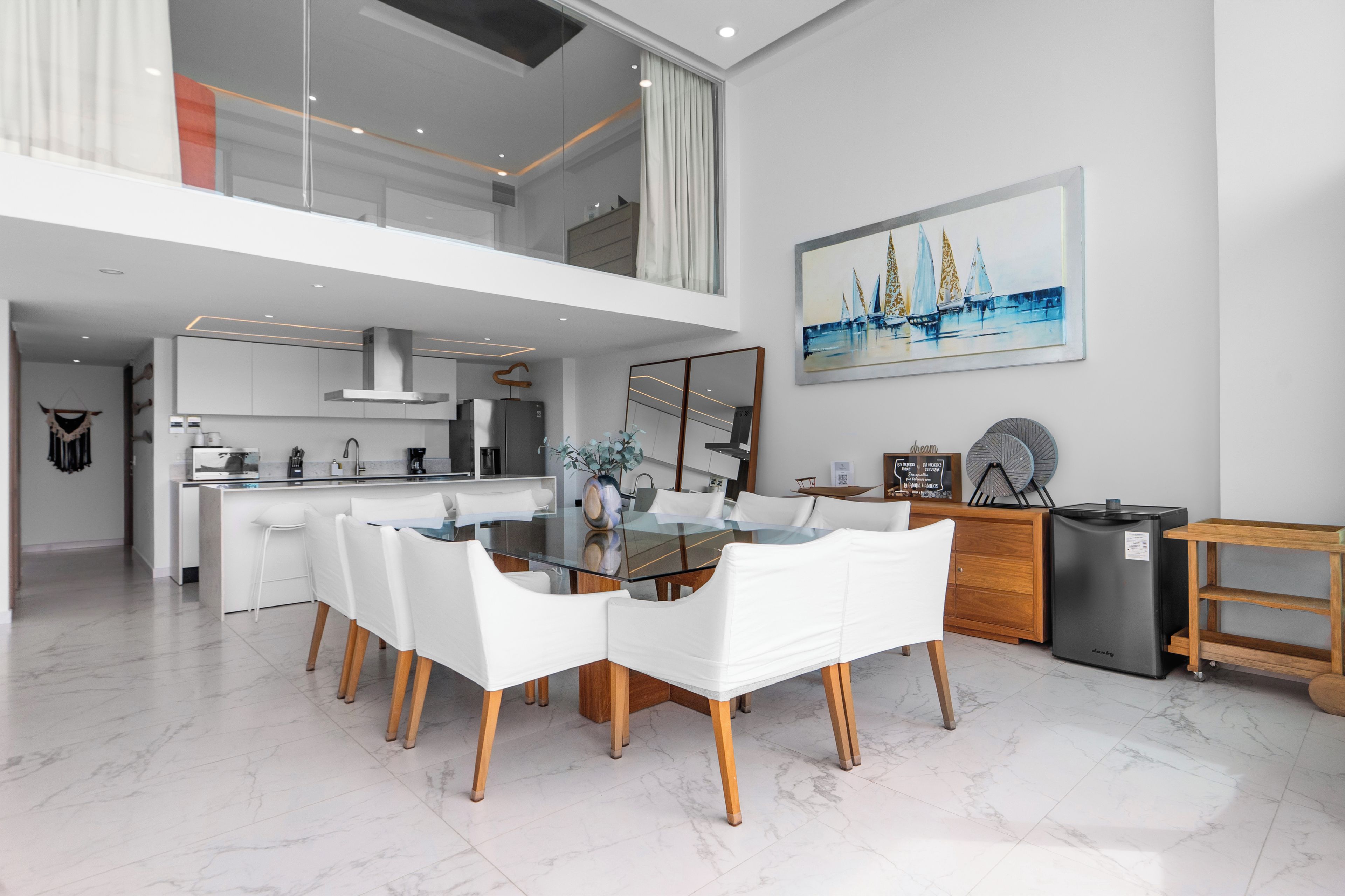 Une cuisine moderne avec une table à manger en verre et des chaises blanches.