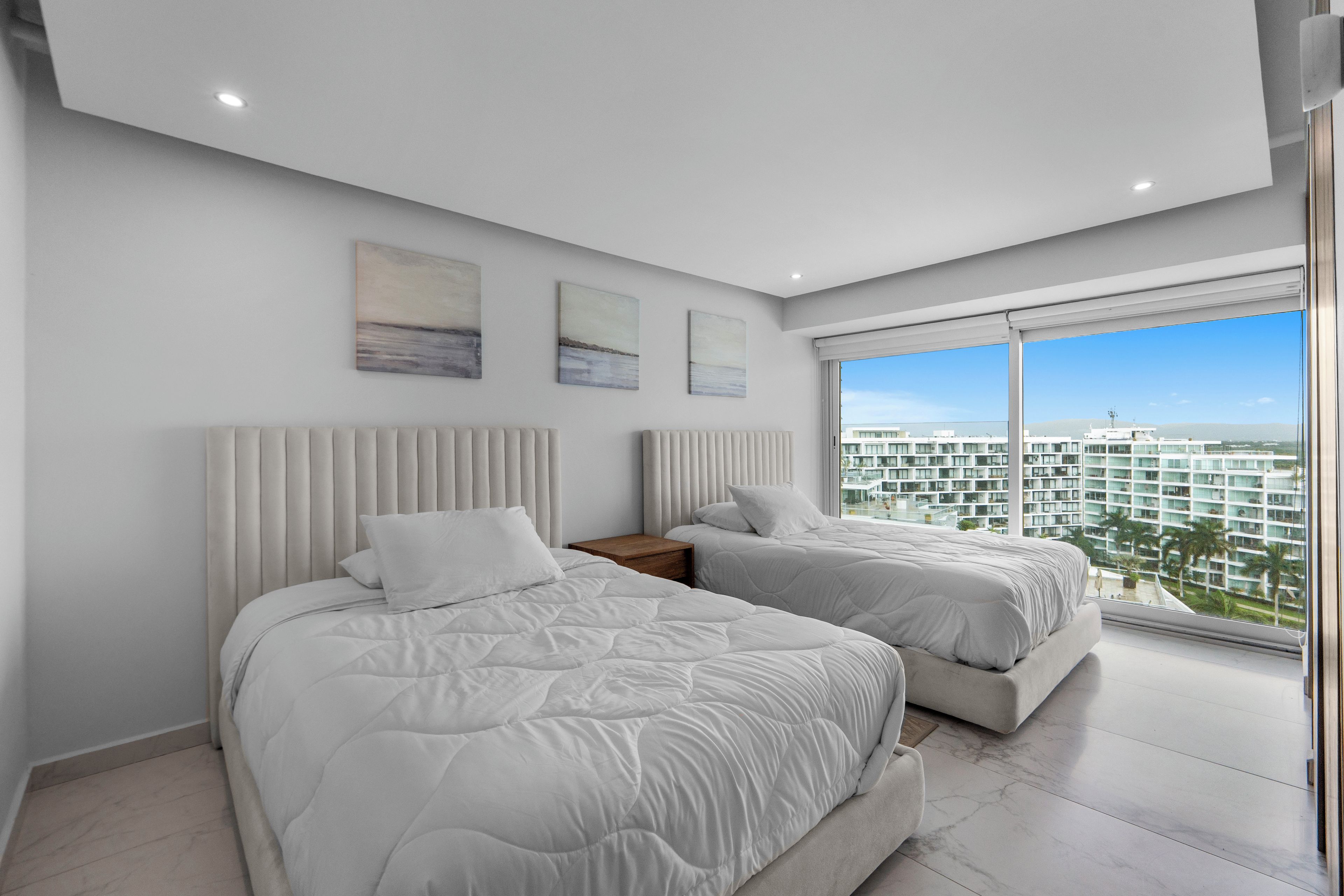 Un dormitorio moderno con dos camas, un ventanal grande y una obra de arte en la pared.