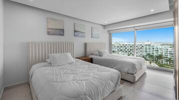 Un dormitorio moderno con dos camas, un ventanal grande y una obra de arte en la pared.