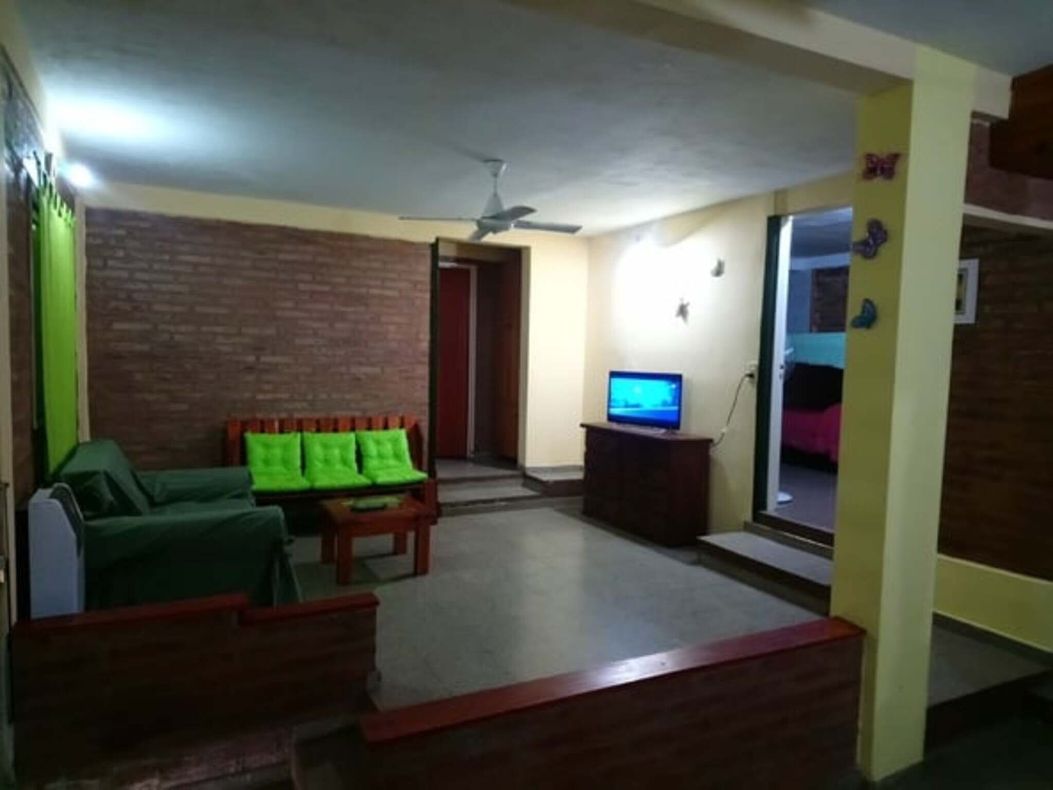 Una sala de estar con un sofá, un televisor y un ventilador de techo.