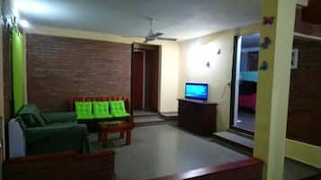 A living room with a sofa, a television, and a ceiling fan.
