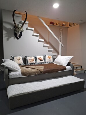 Une chambre moderne avec un lit, des oreillers, un élément décoratif mural et un escalier.