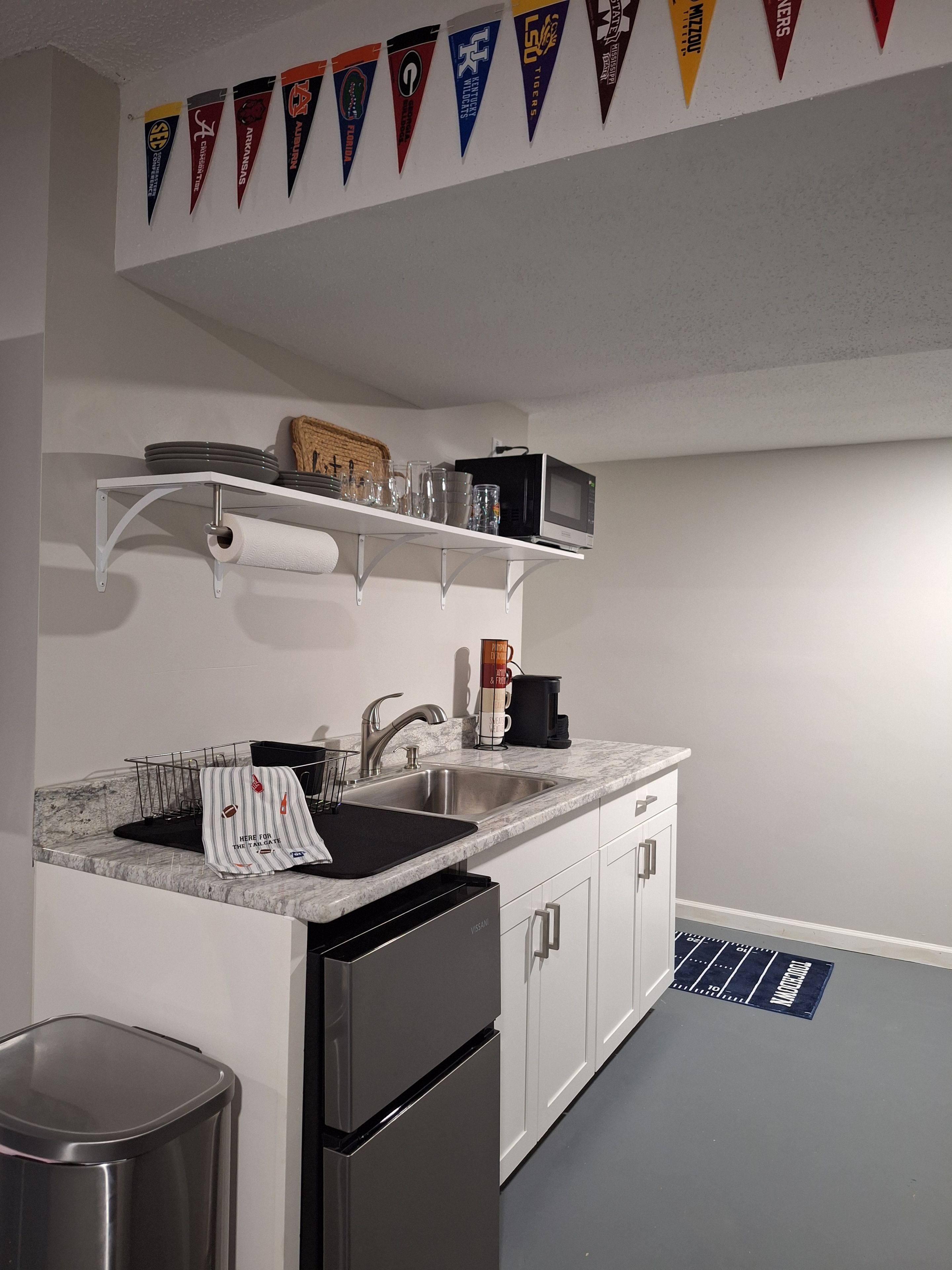 A kitchen with a built-in dishwasher, a sink, and a microwave on a shelf.