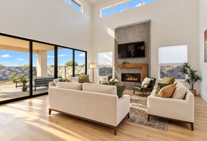 A spacious living room with a fireplace, large windows, and a view of the outdoors. - Hurricane Hideaway - Hot Tub + Ping Pong - Pet Ok! (Hurricane)