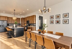 A modern kitchen with wooden cabinets, a central island, bar stools, and pendant lighting. - Hurricane Hideaway - Hot Tub + Ping Pong - Pet Ok! (Hurricane)