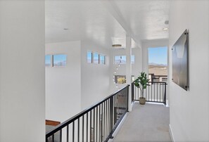 A spacious hallway with a view of the mountains, a black railing, and a potted plant. - Hurricane Hideaway - Hot Tub + Ping Pong - Pet Ok! (Hurricane)