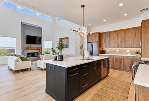A modern kitchen with a large island, wooden cabinets, and a built-in TV. - Hurricane Hideaway - Hot Tub + Ping Pong - Pet Ok! (Hurricane)