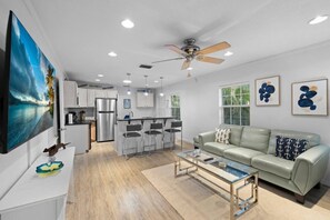 A modern living room with a sofa, coffee table, and a TV mounted on the wall. - Mermaid Cottage | 2BR • Oasis | Madeira Bch (Madeira Beach)
