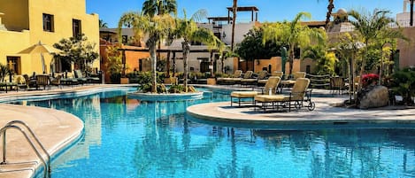 A pool area with lounge chairs and palm trees.