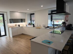 A modern kitchen with white cabinetry, a central island, and a large window.
