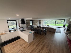 A modern kitchen with a stone accent wall, a dining area with a large window, and a seating area with a view of the outdoors.