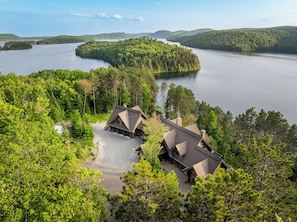 A lodge with a gravel driveway, multiple buildings, and a lake surrounded by forest. - Private Luxury Lodge on Lac Sacacomie, (Saint-Alexis-des-Monts)