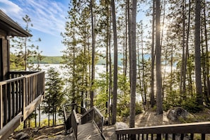 A wooden deck leading to a cabin overlooking a lake surrounded by tall pine trees. - Private Luxury Lodge on Lac Sacacomie, (Saint-Alexis-des-Monts)