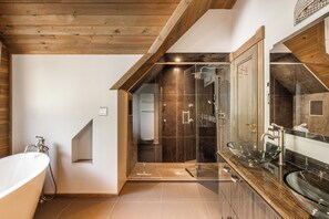 Een moderne badkamer met een vrijstaand bad, een douche met glazen wanden en een grote spiegel.