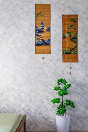 Two vertical wall hangings with traditional designs, a potted bonsai tree, and a wooden bench. - Apartments Zarafshan city 5 Tashkent (Tashkent)