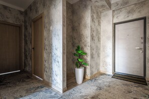 A hallway with marble walls, a wooden door, and a potted plant. - Apartments Zarafshan city 5 Tashkent (Tashkent)