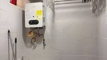 A bathroom with a Bosch water heater, a sink, and a towel rack with various cleaning tools.