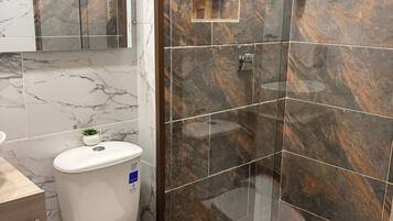 Een badkamer met toilet, bidet en douchecabine met glazen wanden.