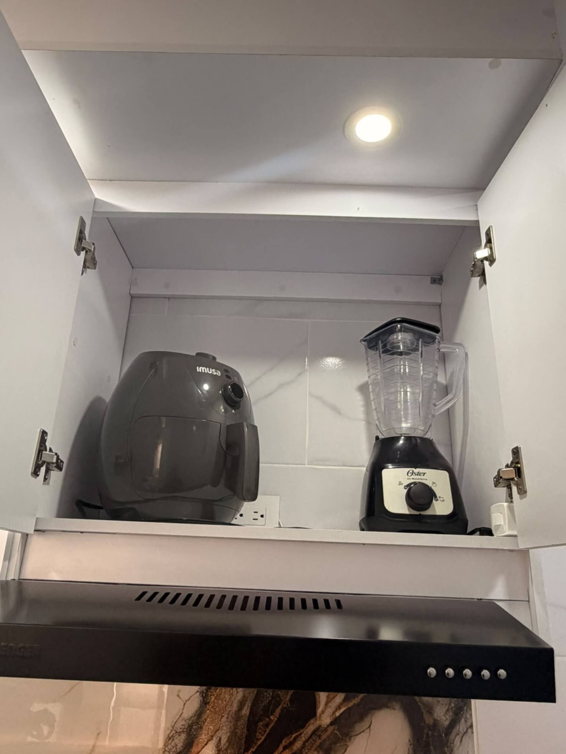 Et køkken med indbygget ovn, blender og kaffemaskine.