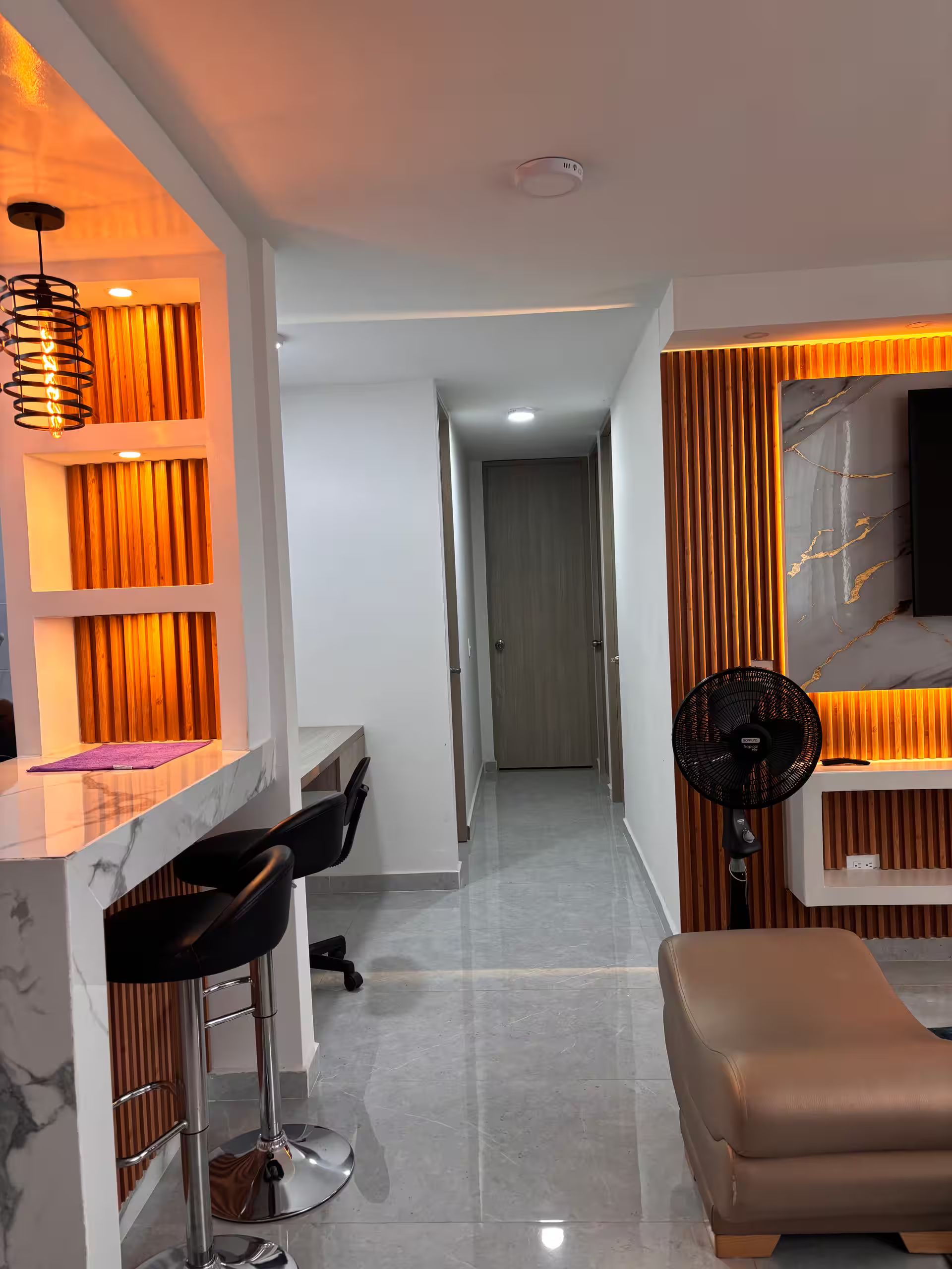 A modern interior with a dining area, a sofa, and a fan.