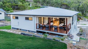 A modern house with a deck, a covered outdoor seating area, and a view of the surrounding landscape. - Coastal Haven | Boat Parking | Walk to Town (Agnes Water)