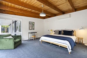 Ein Schlafzimmer mit einem Bett, einem grünen Sessel, einem Schreibtisch und einem Fenster.