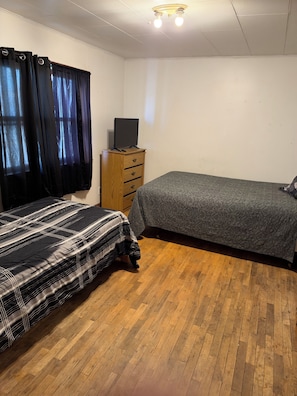 A bedroom with a bed, a dresser, a television on top of the dresser, and a window with curtains. - Delightful 2-bedroom apartment in peaceful Walden perfect for relaxing (Walden)