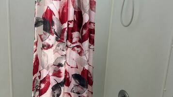 Un área de ducha con cortina decorada con motivos florales.