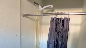 A shower with a curtain, a towel rack, and a showerhead.