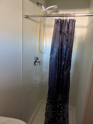 Une douche avec un rideau, un porte-serviettes et un pommeau de douche.