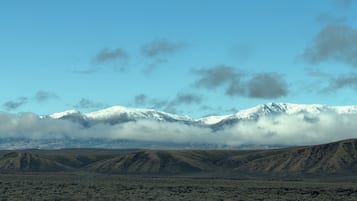 Cordillera nevada y un valle con vegetación escasa.