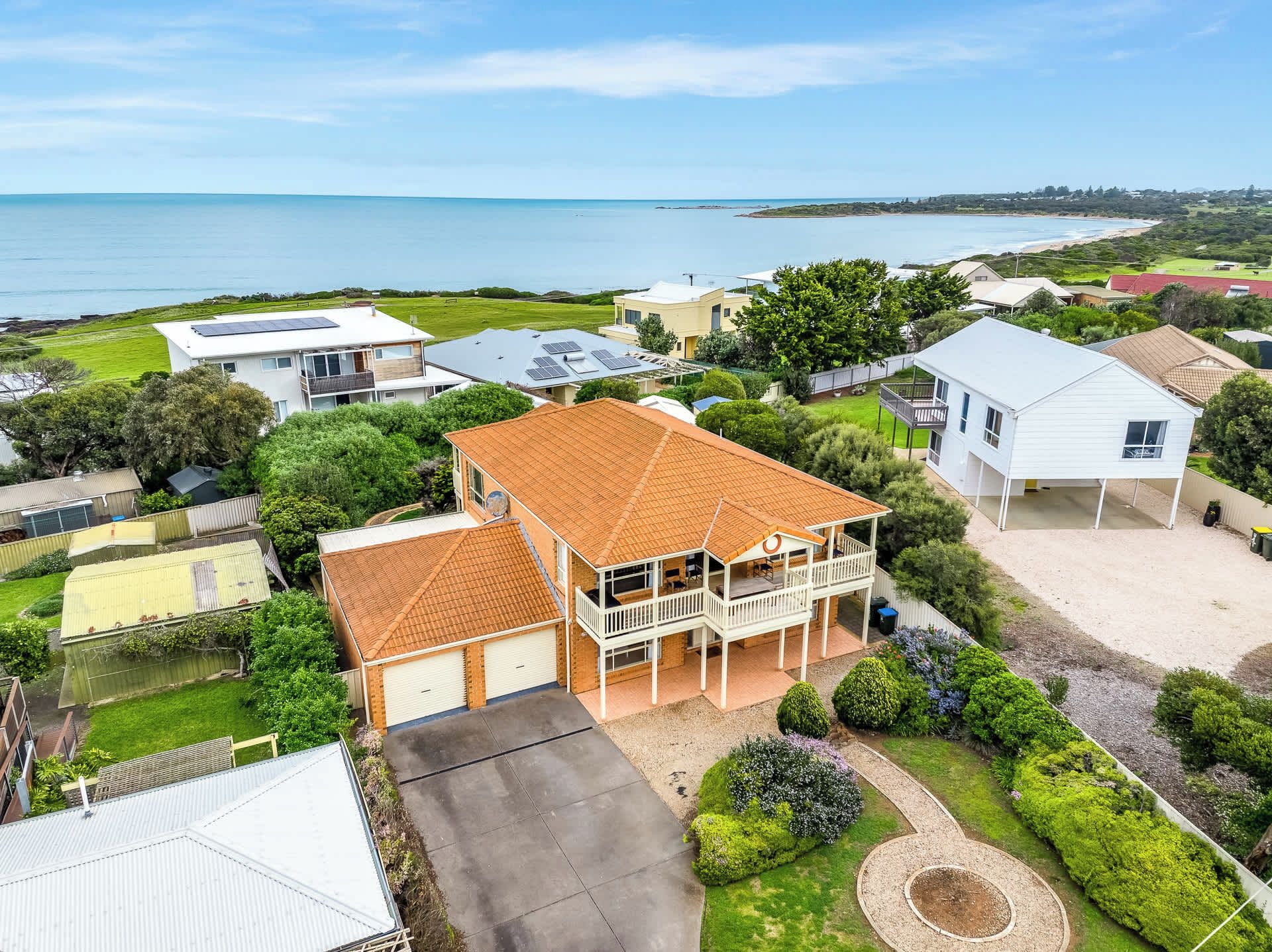 A residential area with houses, a large lawn, and a view of the sea.