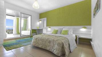 Un dormitorio con cama, escritorio y silla. Hay una ventana con cortinas y vistas al exterior.