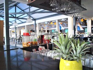 Zona de bar con techo de cristal, una planta amarilla y diversos utensilios.
