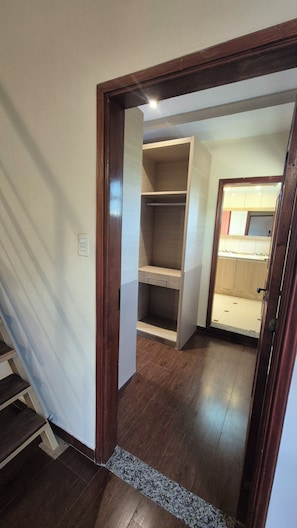 Un pasillo que conduce a un baño con suelo de madera y zona de ducha con azulejos.