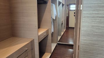 Un vestidor con estantes de madera, un espejo y una barra para colgar ropa.