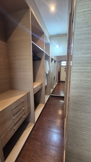 Un vestidor con estantes de madera, un espejo y una barra para colgar ropa.