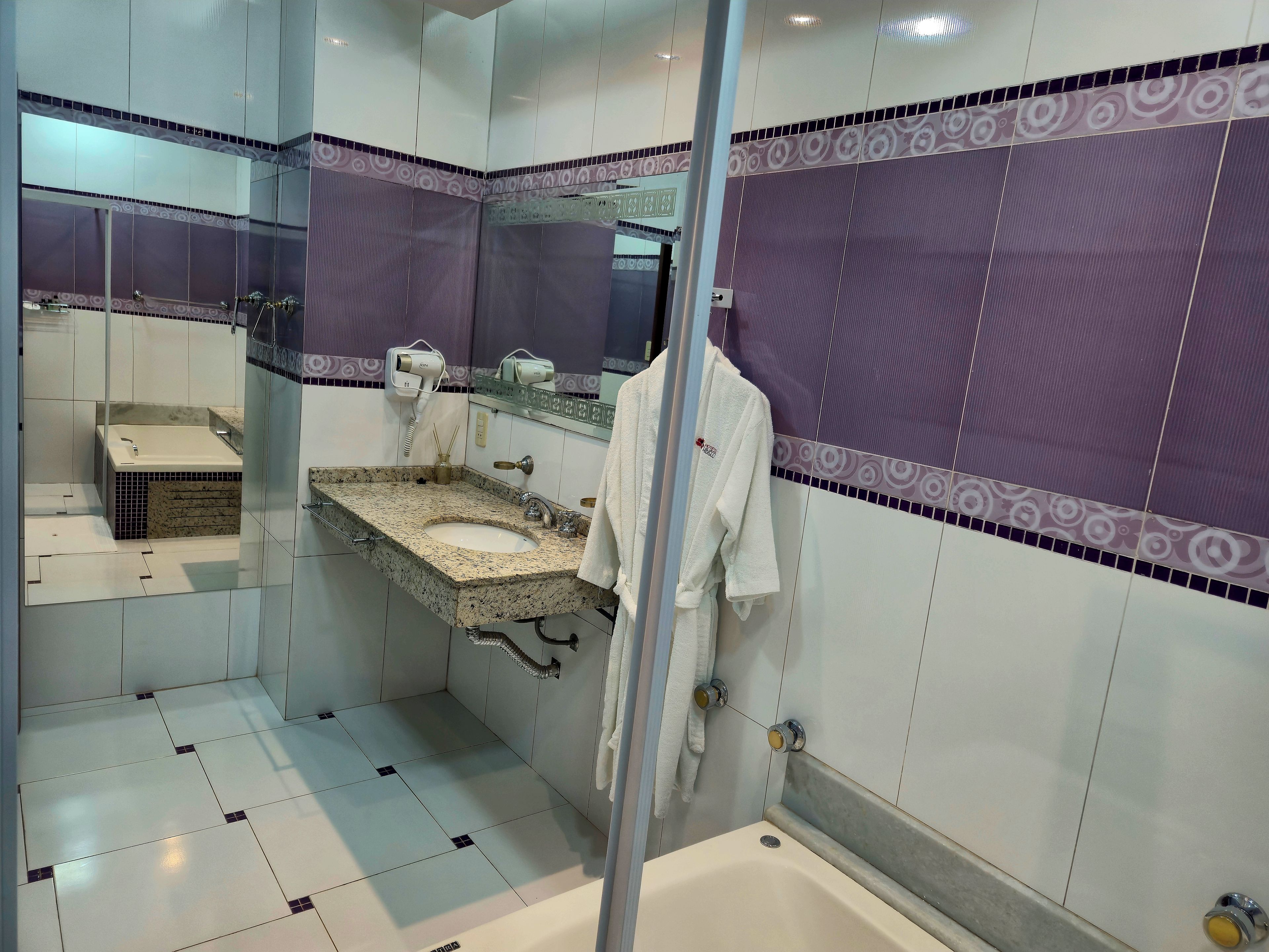 Un baño con lavamanos, espejo, toallero y zona de ducha.