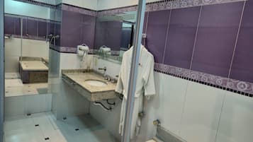 Un baño con lavamanos, espejo, toallero y zona de ducha.