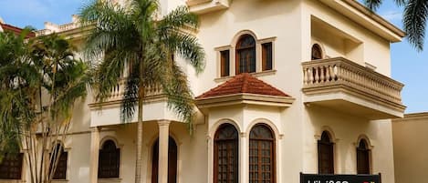 Un edificio de dos plantas con balcón, ventanas de arco y un letrero que dice 'Hibisco Hotel Boutique | Bistrô | Eventos'.