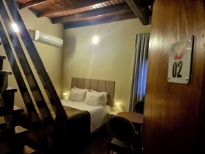 A hotel room with a bed, a desk, a chair, an air conditioning unit, and a number sign. - Hibisco Hotel Boutique (Encarnación)