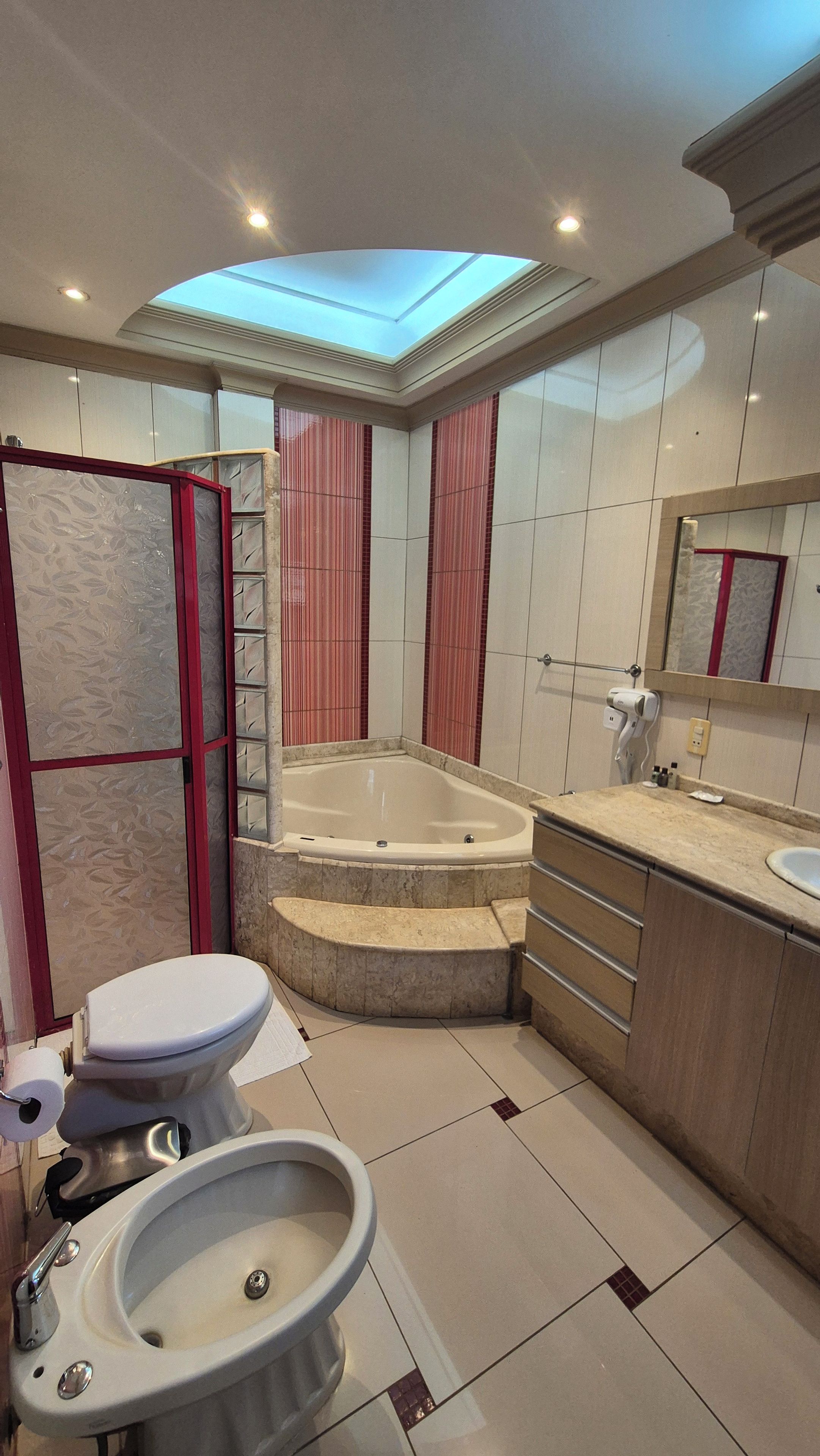 A modern bathroom with a skylight, a bathtub, a toilet, and a sink.
