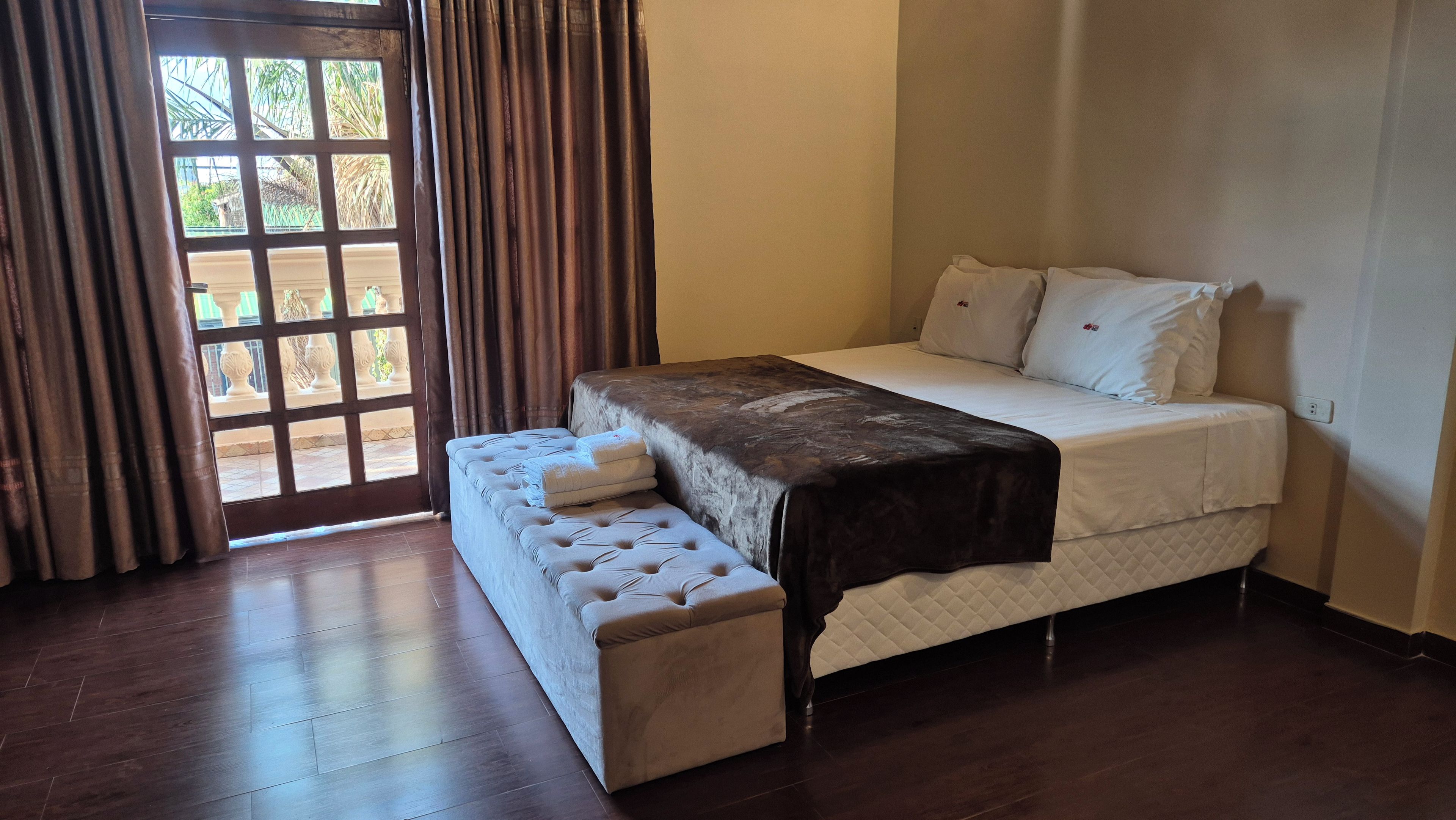 Un dormitorio con una cama, un banco y vistas por la ventana.