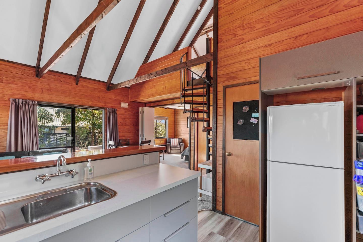 A modern kitchen with a large island, stainless steel sink, and a refrigerator.